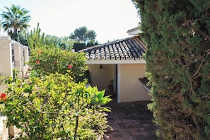 A residential property with a tiled roof, a brick entrance, and a garden with various plants and flowers.