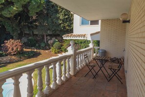 A balcony with a white balustrade, a small table with chairs, and a brick wall.