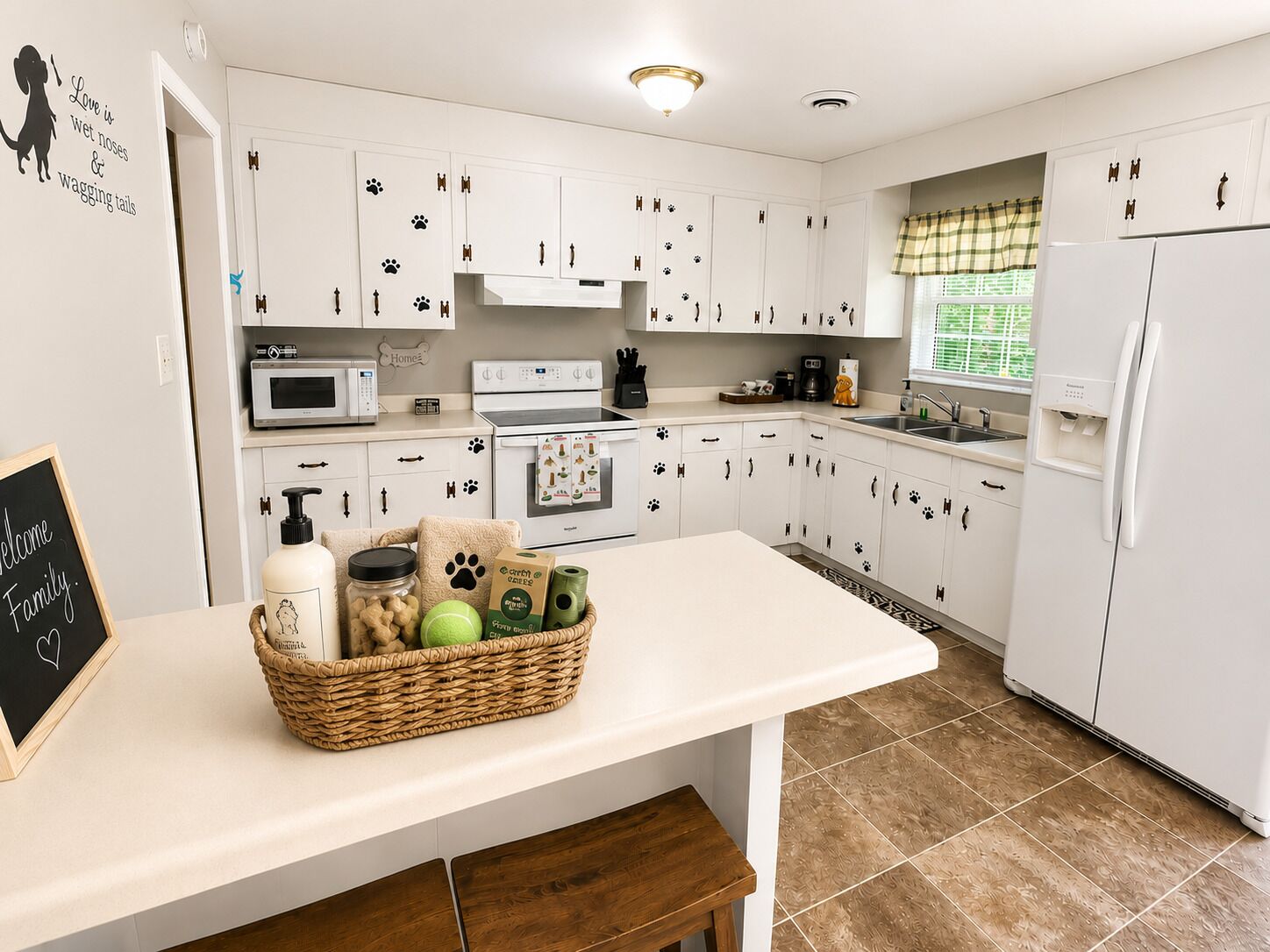 A kitchen with white cabinets, a microwave, a stove, and a refrigerator. There is a basket on the counter with food items.