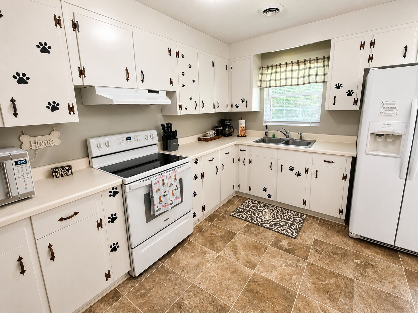 A kitchen with white cabinets, a stove, a refrigerator, and a window with a view.
