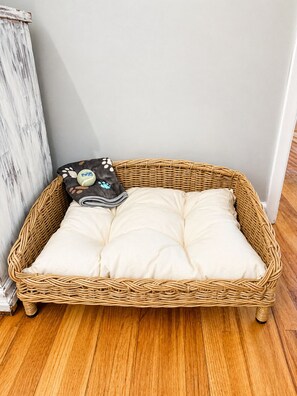 A wicker basket with a white cushion and a polka-dotted pillow. - Dog Lovers' Dream  Wash Station + Dog Library (Warner Robins)