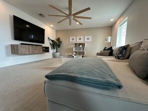 A modern living room with a flat-screen TV, ceiling fan, and a sofa with a folded blanket. - Tempe Luxury Oasis 10 mins from ASU, Old Town and PHX (Tempe)