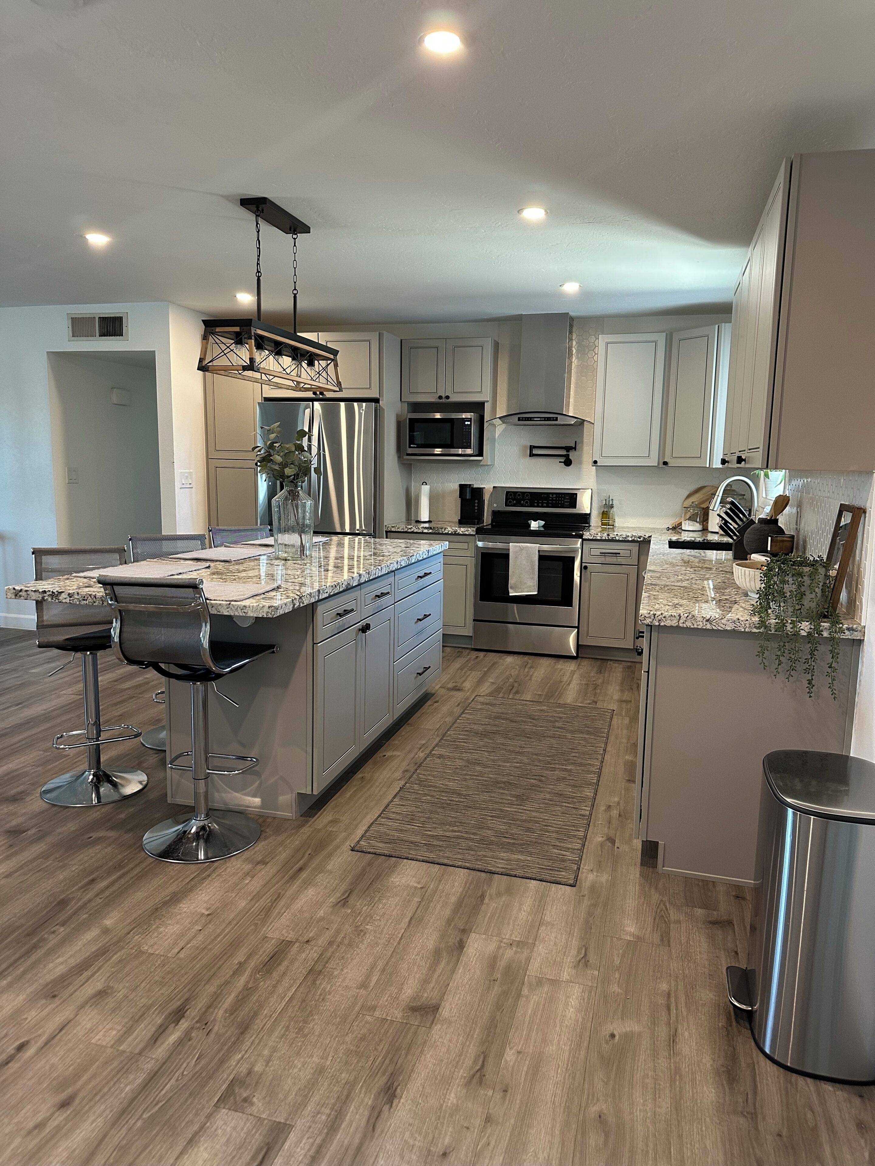 A modern kitchen with a central island, stainless steel appliances, and bar stools.