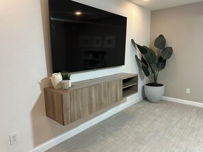 A flat-screen TV mounted on a wall with a wooden console below. - Tempe Luxury Oasis 10 mins from ASU, Old Town and PHX (Tempe)