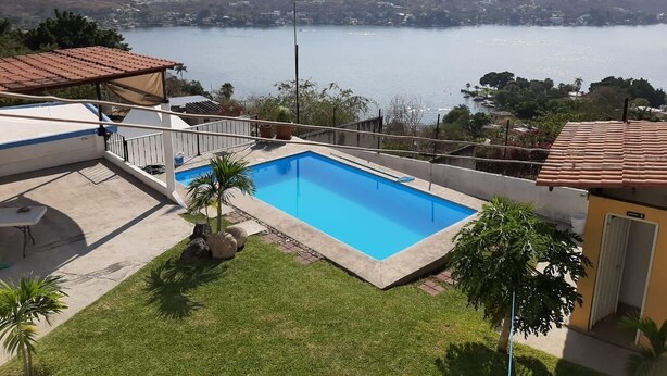 Una piscina con vistas a un lago y montañas al fondo.