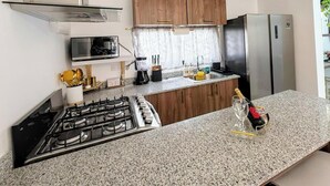 Eine moderne Küche mit Gaskochfeld, Edelstahlgeräten, Holzschränken und einer Granit Arbeitsplatte.