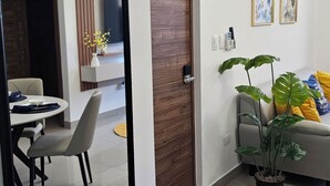 Ein modernes Wohnzimmer mit Essbereich, einem großen Spiegel, einer Holztür und einem Blumentopf.