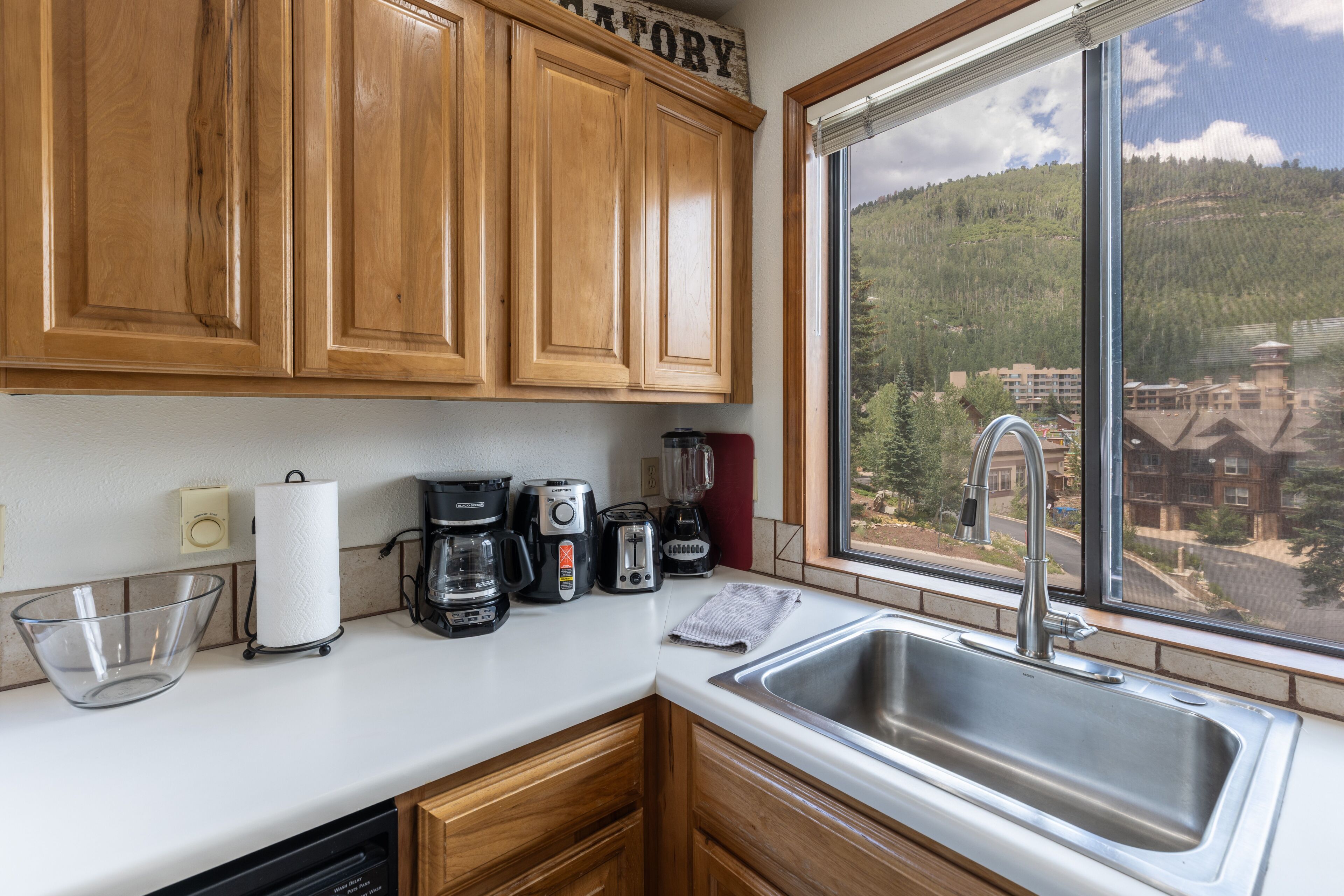 A kitchen with wooden cabinets, a coffee maker, a toaster, and a sink.