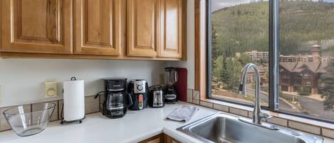 A kitchen with wooden cabinets, a coffee maker, a toaster, and a sink.