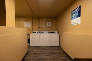 A laundry room with a row of washers and dryers, a poster advertising a mobile app, and a framed picture on the wall. - Your Basecamp! Responsive host! Best deal! (Durango)