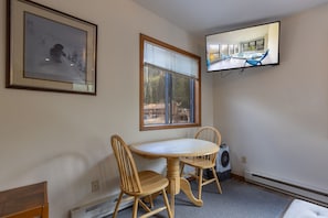 A room with a dining table and chairs, a mounted television, a window with blinds, and a framed picture on the wall. - Your Basecamp! Responsive host! Best deal! (Durango)