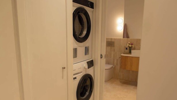 Ein Waschraum mit einer Waschmaschine und einem Trockner, einer Toilette und einem Waschbecken mit Spiegel.