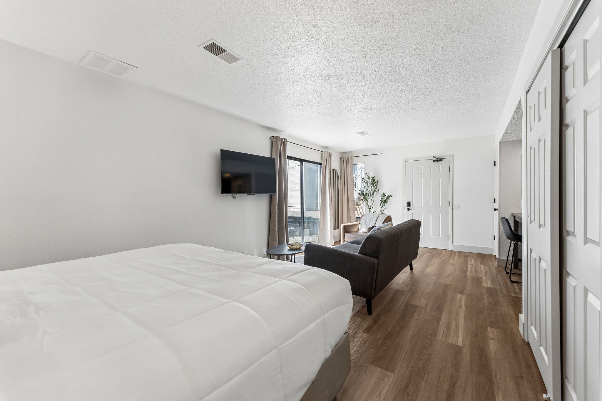 Une chambre d’hôtel comprenant un lit, un bureau, une chaise, une télévision et une porte donnant sur une autre pièce.