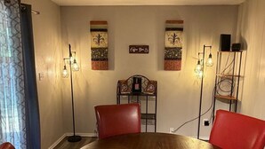 Ein Essbereich mit einem runden Holztisch, roten Stühlen, einer Kaffeebar und Wandleuchten.