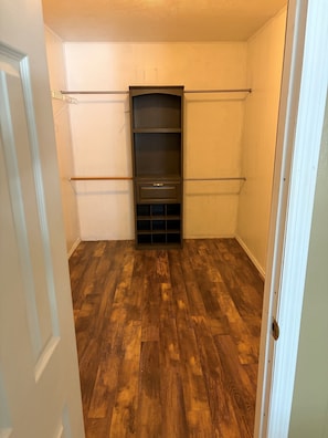 A room with a wooden floor, a built-in shelving unit, and a white door.