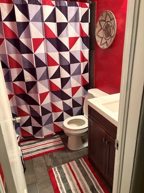 Un baño con cortina de ducha de estampado geométrico, un inodoro y un lavabo.