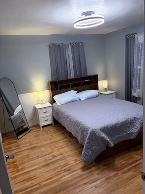 Un dormitorio con cama, mesitas de noche, un espejo y una lámpara en el techo.