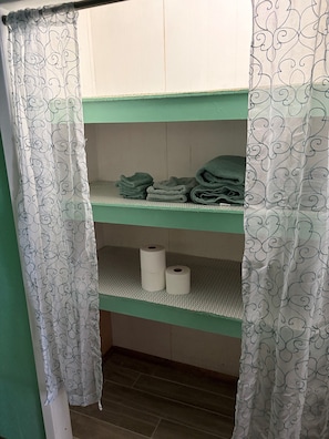 A bunk bed with green-painted lower bunk and white curtains with a leaf pattern.