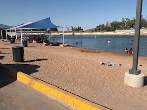 Una playa con una zona de estar techada, un basurero y una barrera de hormigón.