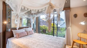 Quarto com cama grande, varanda e vista, e uma cadeira.