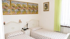 Een slaapkamer met twee bedden, een nachtkastje, een lamp, een teddybeer en een schilderij aan de muur.
