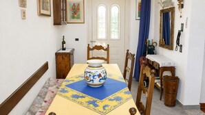 Een eetgedeelte met een tafel gedekt voor twee personen, een vaas op tafel en een houten stoel.