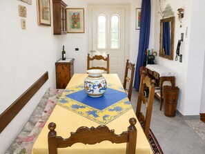Ein Essbereich mit einem Tisch, gedeckt für zwei Personen, einer Vase auf dem Tisch und einem hölzernen Stuhl.