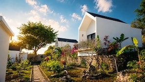A modern house with a stone wall, a pathway, and various plants. - Penida Cabins (Penida Island)