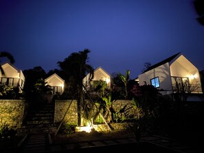 Filas de villas modernas, blancas y de dos pisos con balcones, rodeadas de exuberante vegetación tropical y muros de piedra.