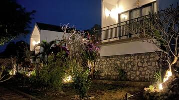 A modern house with a stone facade, a balcony with a railing, and a well-lit entrance.