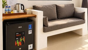 Een moderne kamer met een groot raam, een bank, een bijzettafeltje, een GEA koelkast en een bord met het ontbijtmenu.