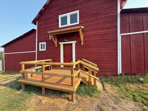 Ein rotes Backsteingebäude mit einer Holzterrasse und einer roten Tür.