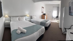 Habitación de hotel con dos camas, un escritorio, una silla y un televisor.