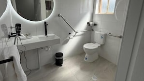 Un baño moderno con inodoro, lavamanos y dos espejos redondos.