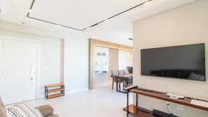 Ein modernes Wohnzimmer mit Flachbildfernseher, einem Essbereich mit Tisch und Stühlen sowie einer Bank.