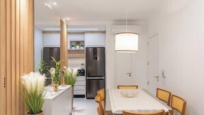 A compact kitchen with modern appliances, a dining area with a table and chairs, and a pendant light fixture. - Ap With sea View Near the Beach in Itapema Alx0803 (Itapema)