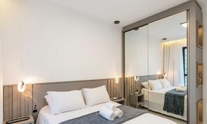 A hotel room with a large bed, a bedside table, a nightstand, a mirror, and a wall-mounted light fixture. - Ap With sea View Near the Beach in Itapema Alx0803 (Itapema)