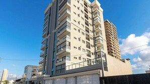 Un immeuble résidentiel à plusieurs étages, doté de balcons, d’un garage et surplombant un ciel dégagé.