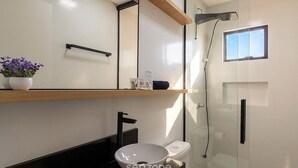 Une salle de bain moderne avec une douche à parois de verre, un lavabo blanc et des toilettes.