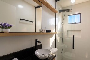 Ein modernes Badezimmer mit einer Duschkabine aus Glas, einem weißen Waschbecken und einer Toilette.