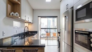 Une cuisine moderne dotée d’un îlot central, d’appareils électroménagers en acier inoxydable et offrant une vue sur la ville grâce à une grande fenêtre.