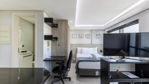A modern hotel room with a bed, desk, chair, and a television. - Apt. in Condo. w/ Heated Pool Sak1138 (Curitiba)