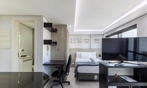 A modern hotel room with a bed, desk, chair, and a television. - Apt. in Condo. w/ Heated Pool Sak1138 (Curitiba)