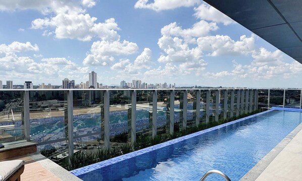 A rooftop infinity pool with a city view, surrounded by a glass railing. - Apt. in Condo. w/ Heated Pool Sak1138 (Curitiba)