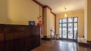 Ein Empfangsbereich mit einem Holzbüro, einem Fernseher und einer dekorativen Tür mit geometrischem Muster.