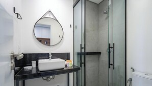 A modern bathroom with a round mirror, a sink, and a glass-enclosed shower. - Apt. w/ Balcony in Condo. 500m From Beach Lan0204 (Florianópolis)
