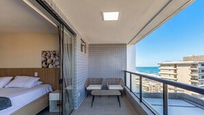 A balcony with a bed, a seating area, and a view of the sea. - Ap With Jacuzzi and sea View in Ilheus, BA Cdw0102 (Ilhéus)