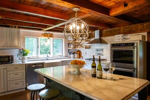 A kitchen with a large island, a microwave, a stove, and a wine bottle. - An Unforgettable Escape at the Hammer House at Three Hammers Winery. (Hawley)