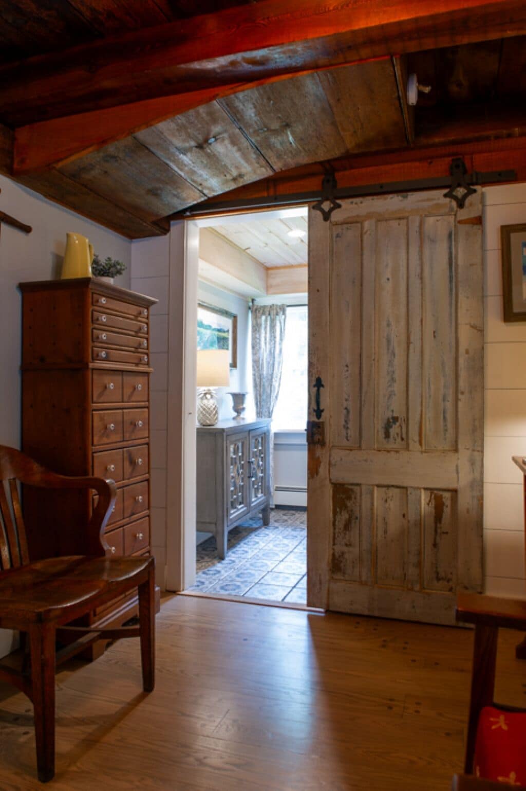 Un intérieur rustique avec une chaise en bois, un meuble en bois et une porte donnant sur une autre pièce.