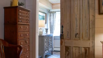 Un intérieur rustique avec une chaise en bois, un meuble en bois et une porte donnant sur une autre pièce.